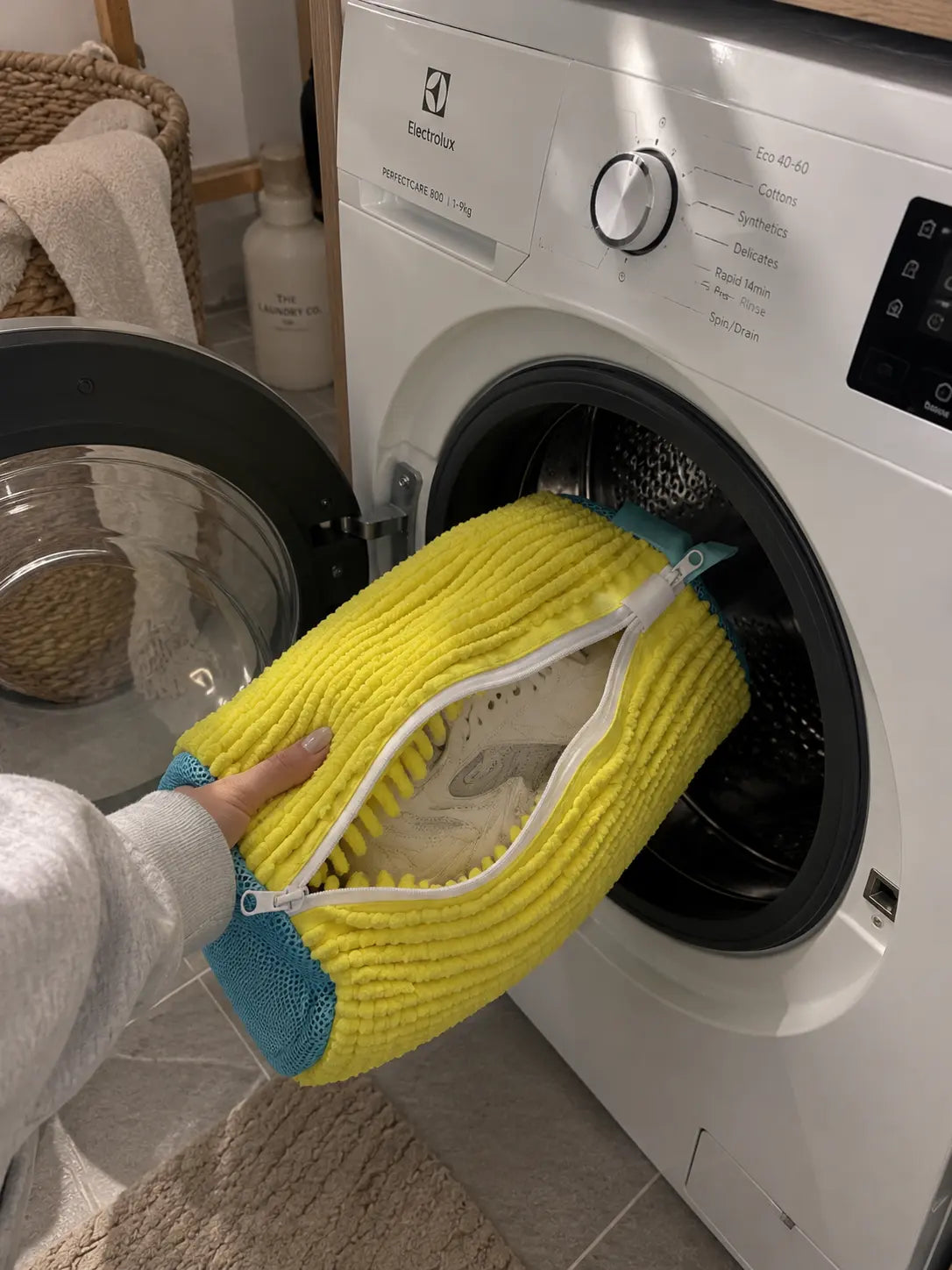 SOLEVA yellow sneaker wash bag going into a washing machine